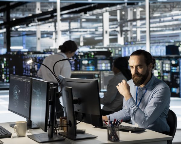 Technician using PC in data center to update server tech, configuring equipment using software tools. Server room employee reviewing hardware analytics, ensuring reliable network operations